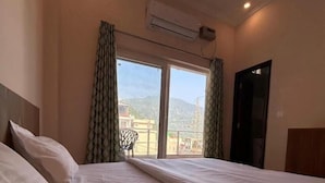 Een hotelkamer met twee bedden, een balkon en uitzicht op de bergen.