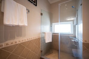Ein modernes Badezimmer mit einer einteiligen Duschkabine, beigen Fliesen und einem Fenster, das für natürliches Licht sorgt.