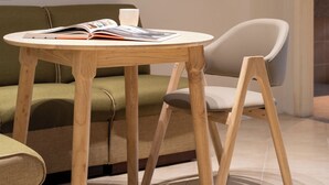 Una habitación con una mesa redonda de madera, un sofá verde y una silla blanca.