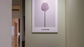 Una obra de arte enmarcada con una flor etiquetada como "VIETNAM" en una pared de un pasillo.