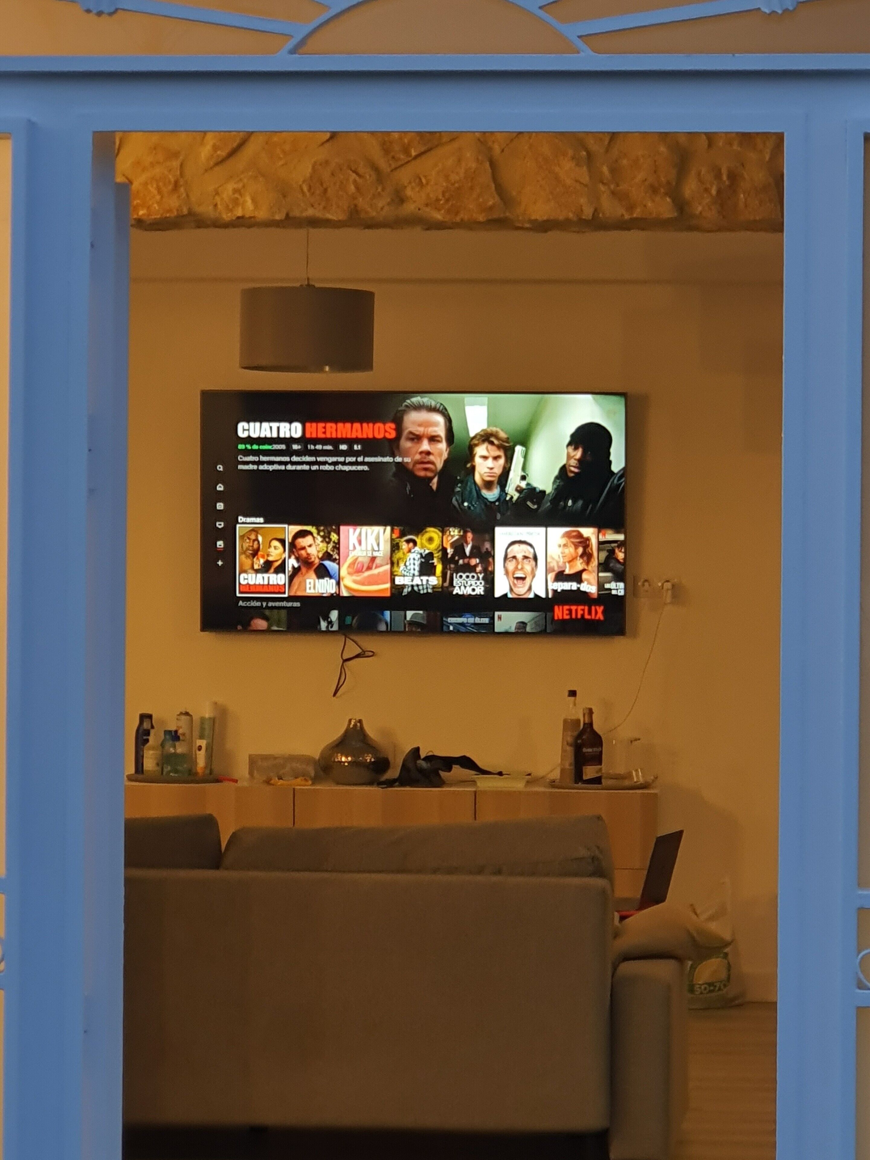 Ein an der Wand befestigter Fernseher zeigt eine Streaming-Oberfläche mit verschiedenen Filmangeboten.