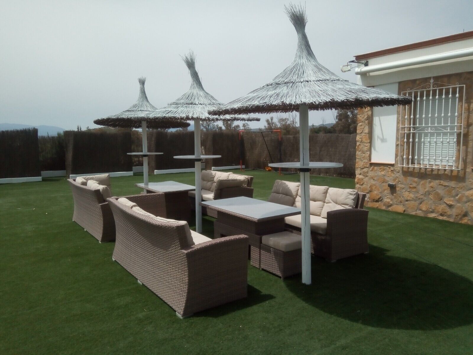 A patio with wicker furniture, a stone wall, and a view of the landscape.