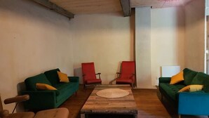 Una habitación con dos sofás verdes, una mesa de centro de madera y dos sillas rojas.