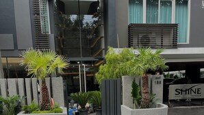 A modern building with a gated entrance, potted plants, and a sign for 'SHINE THONGLOR SERVICED RESIDENCE'. - Shine Thonglor (Bangkok)