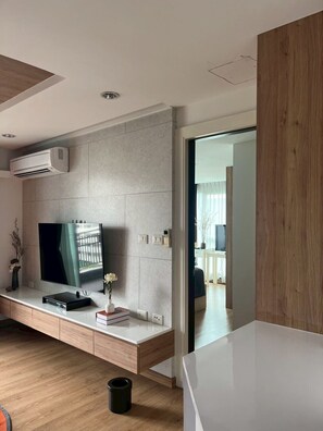A modern living room with a flat-screen TV, a built-in air conditioner, and a minimalist design. - Shine Thonglor (Bangkok)