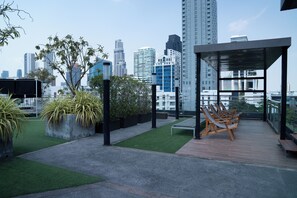 A rooftop terrace with a city skyline, outdoor seating, and planters. - Shine Thonglor (Bangkok)
