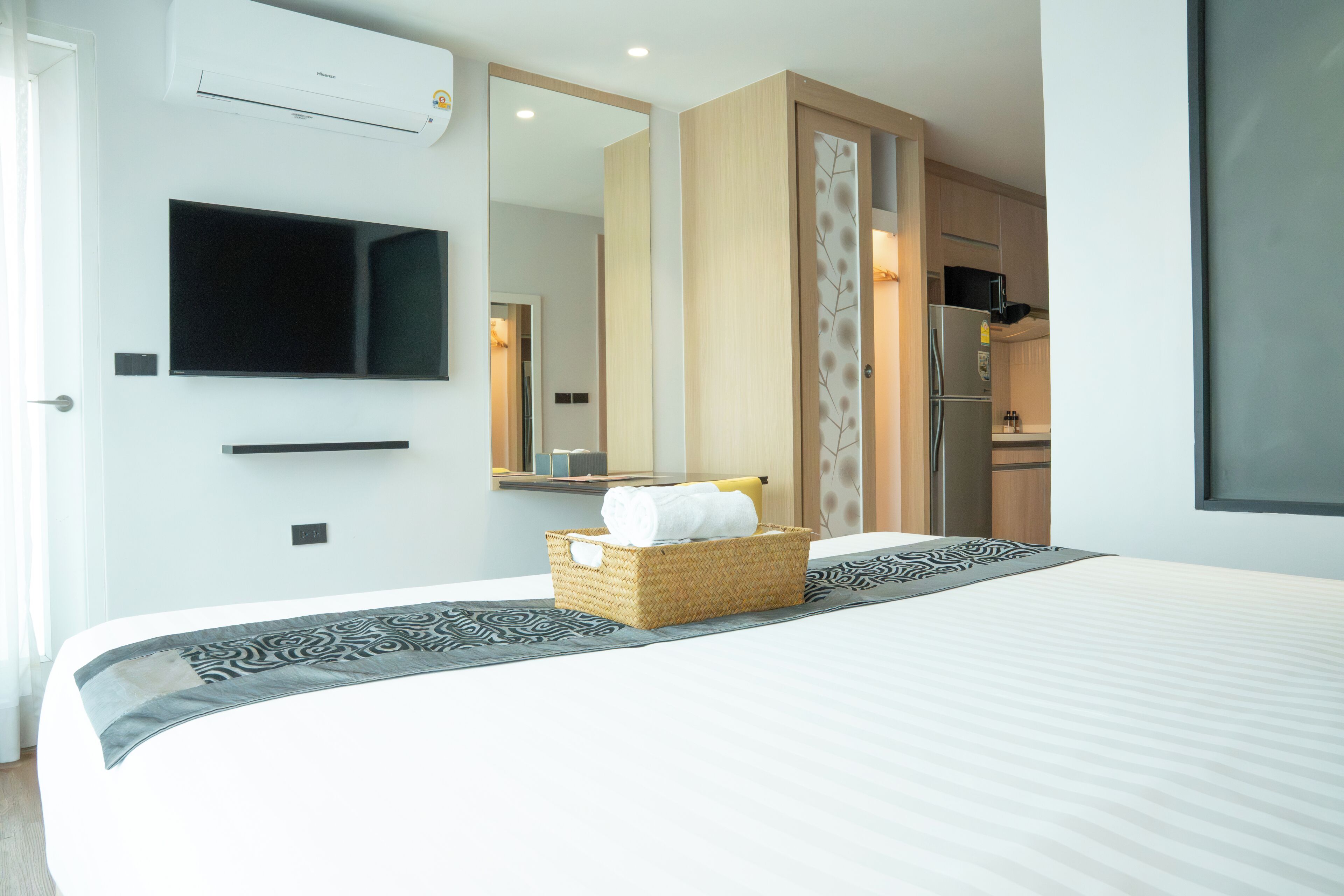 Une chambre d’hôtel équipée d’un lit, d’une télévision, d’un miroir, d’un réfrigérateur et d’un coin cuisine.