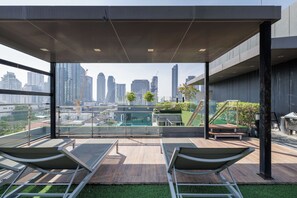 A rooftop terrace with lounge chairs, a small pool, and a city view. - Shine Thonglor (Bangkok)