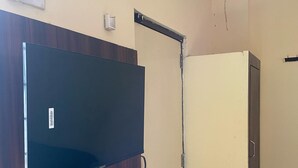 Une pièce dotée d’un téléviseur à écran plat fixé sur un panneau en bois, d’une armoire de couleur crème et d’une porte avec une poignée en métal.