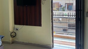 Une pièce équipée d’un téléviseur fixé au mur, d’un appareil de climatisation et d’une porte donnant sur l’extérieur.