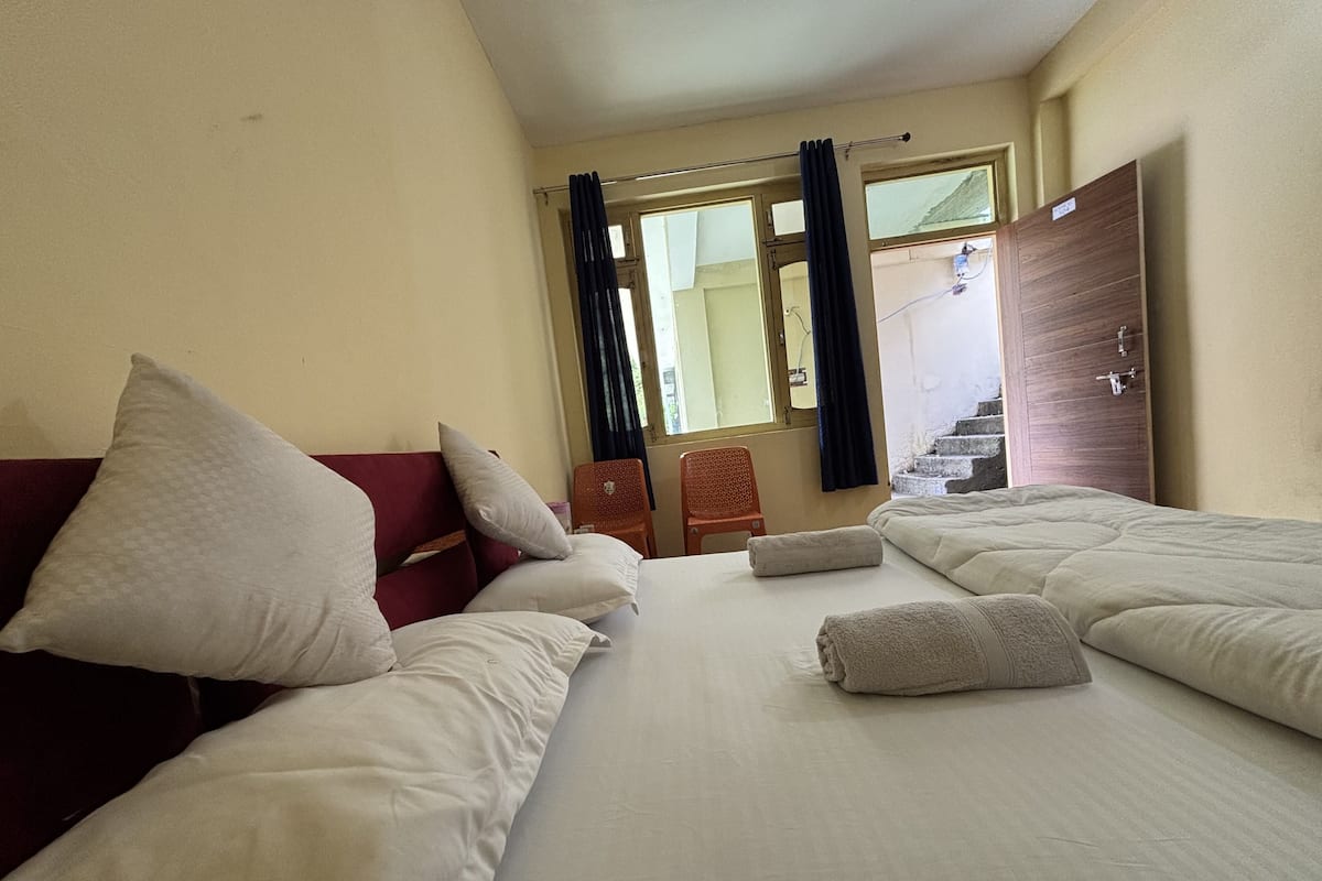 Habitación de hotel con dos camas, cabecera roja y ventana con cortinas.