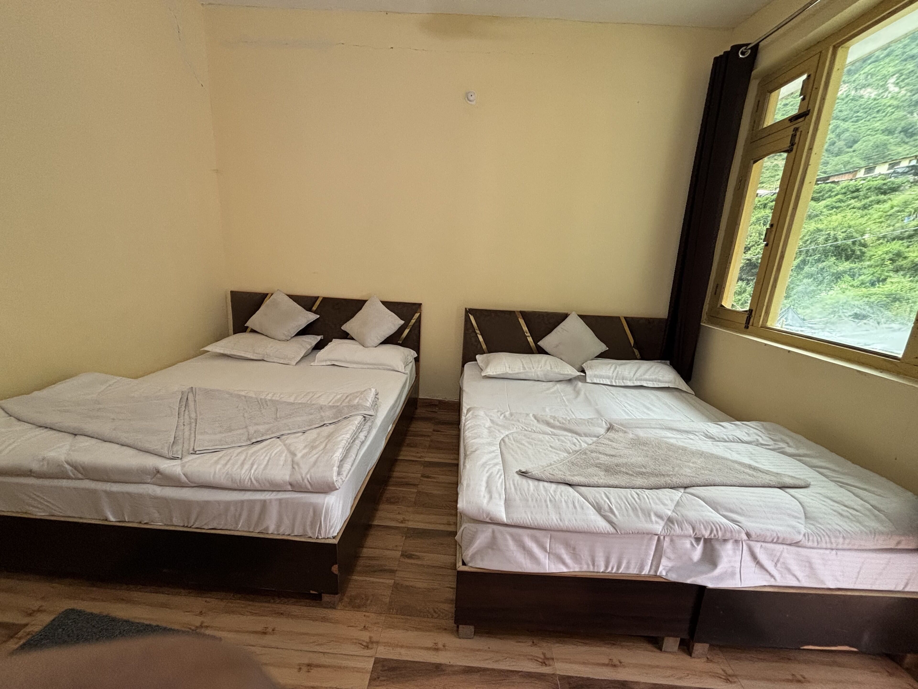 A room with two beds, each with a wooden headboard and white bedding.