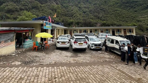 A parking area with several cars and a building with a signboard. - AP Residency Yamunotri (Rajgarhi)