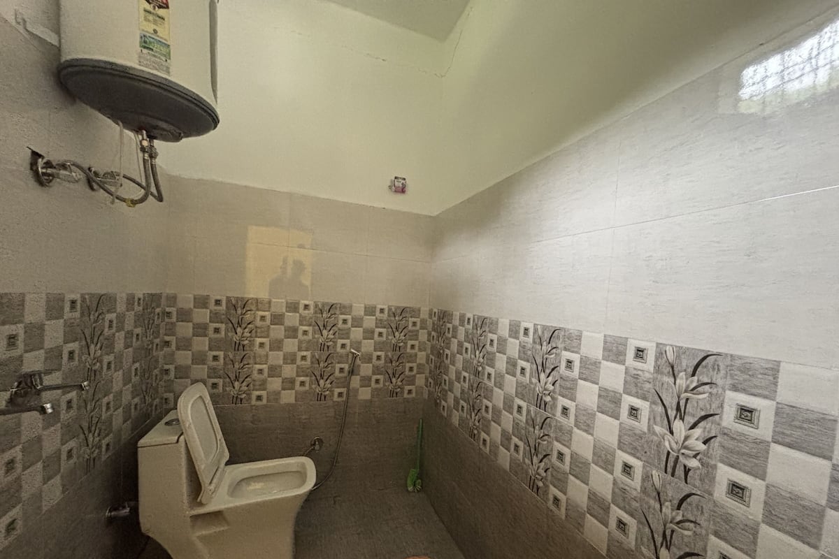Un baño con inodoro, ducha y paredes de azulejos con un estampado de cuadros.