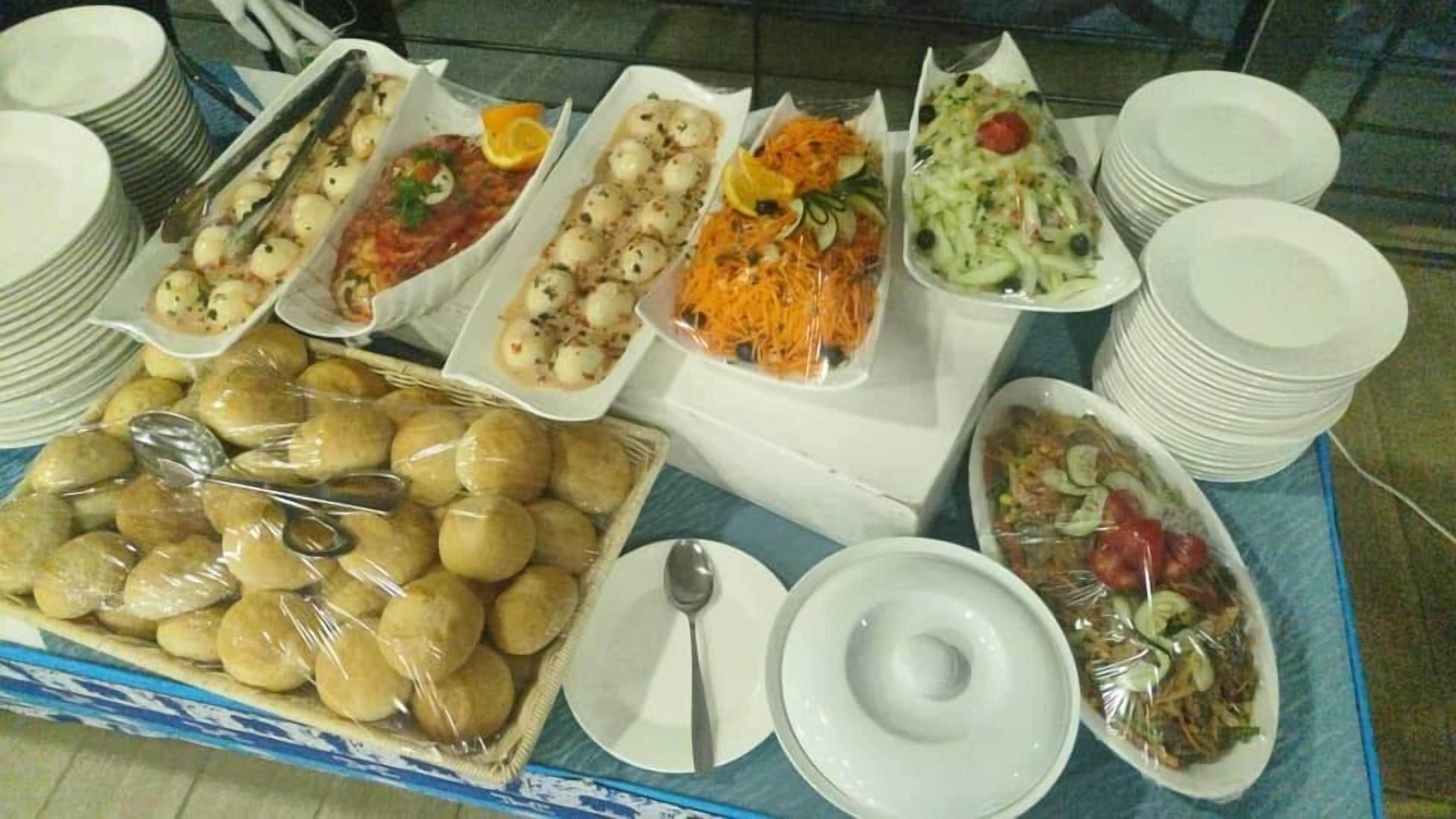 A buffet table with various dishes, plates, and utensils.