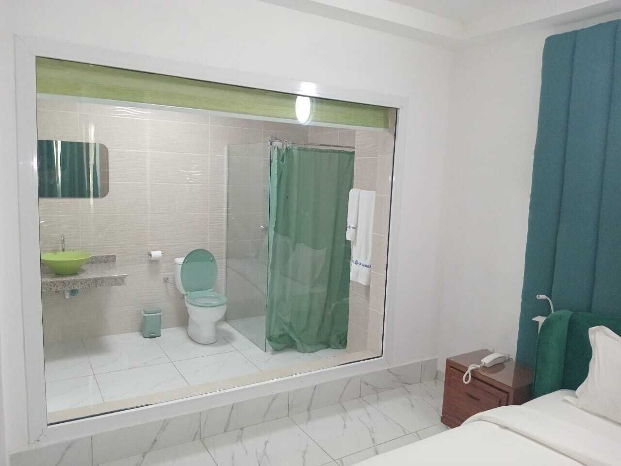 A modern bathroom with a glass shower enclosure, a green sink, and a white toilet.