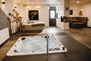 Moderni spa-huone, jossa on poreallas, sohva ja portaikko.