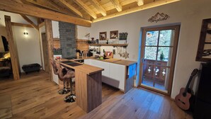 A kitchen with wooden beams, a stone wall, and a large window.