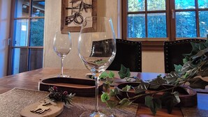 A dining area with a wooden table, two wine glasses, a decorative plate, and a framed picture on the wall.