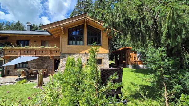 A lodge with a stone facade, large windows, and a wooden deck.
