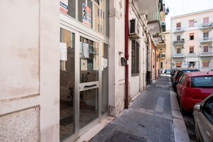 Una stretta via con auto parcheggiate e un edificio con porta e finestre in vetro.