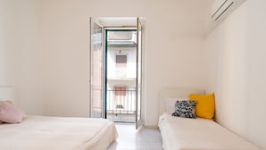 A bedroom with two beds, a window, and an open door leading to a balcony. - Rifugio Pugliese by Wonderful Italy (Bari)