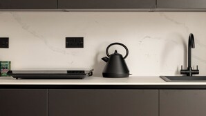 A modern kitchen with a sleek countertop, a kettle, and a faucet. - Moment Blythswood Street (Glasgow)
