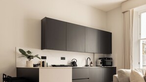 A modern kitchen with dark cabinets, a marble island, and a minimalist design. - Moment Blythswood Street (Glasgow)