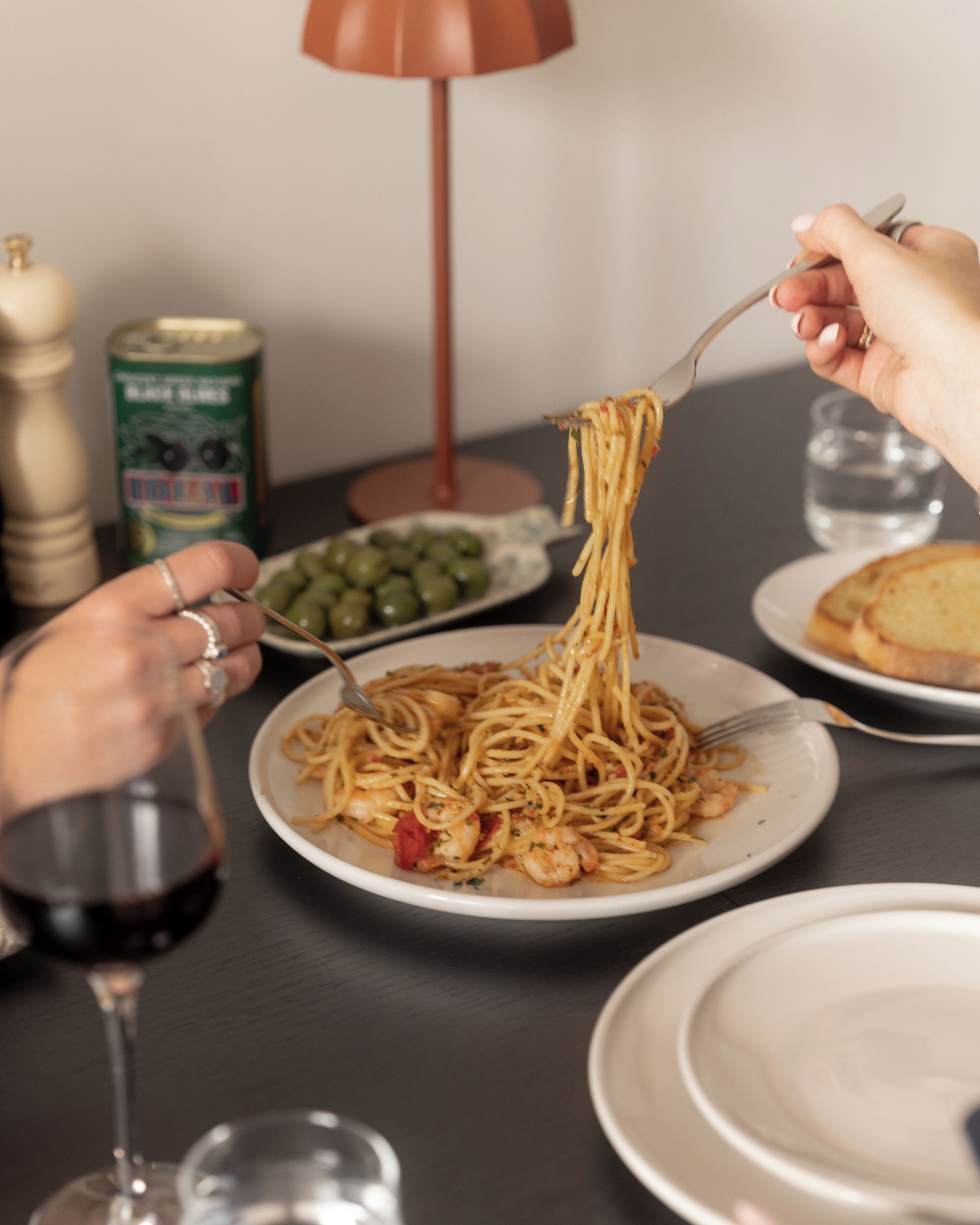 Ein Esstisch mit Tellern Spaghetti, einer Limodose und einem Glas Rotwein.