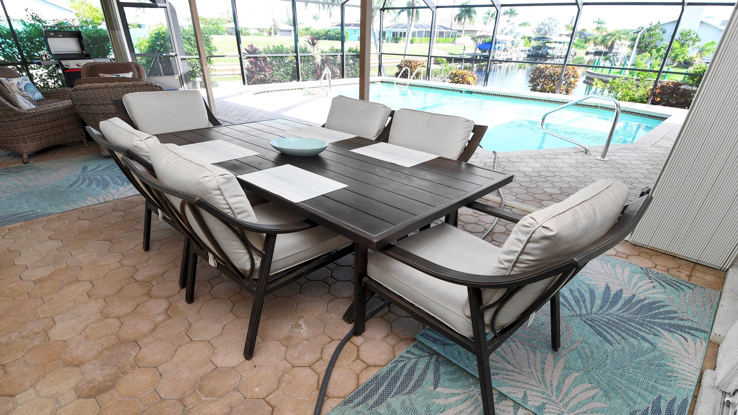 A patio with a pool table, chairs, and a view of a swimming pool.