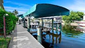 A dock with a covered walkway, a boat, and a calm water body.