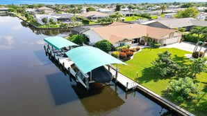 A houseboat docked at a marina with a covered deck and a well-maintained lawn.