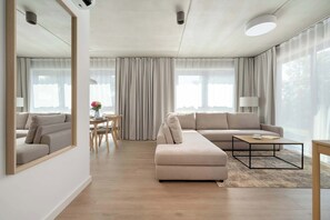 A modern living room with a sofa, coffee table, and a dining area with a table and chairs. - Elegant Apartment | Air Conditioning, Balcony, Parking (Wrocław)