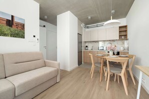A modern interior with a sofa, dining table, and kitchen area.