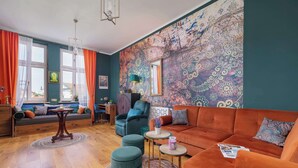 Een woonkamer met een bank, poufs, een salontafel en een behang met patroon.