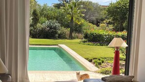 A room with a view of a swimming pool, a sofa, and a lamp. - EXCEPTIONAL VILLA - GOLF - SWIMMING POOL - BREAKFAST AND SERVICES (essaouira)