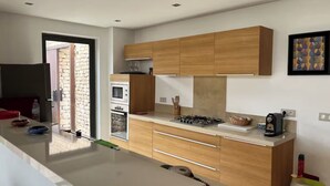A modern kitchen with wooden cabinets, a gas stove, and a built-in oven. - EXCEPTIONAL VILLA - GOLF - SWIMMING POOL - BREAKFAST AND SERVICES (essaouira)