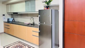 Eine moderne Küche mit einem Edelstahl-Kühlschrank, Holzschränken, einer schwarzen Arbeitsplatte und einem kleinen Topf mit Pflanze darauf.