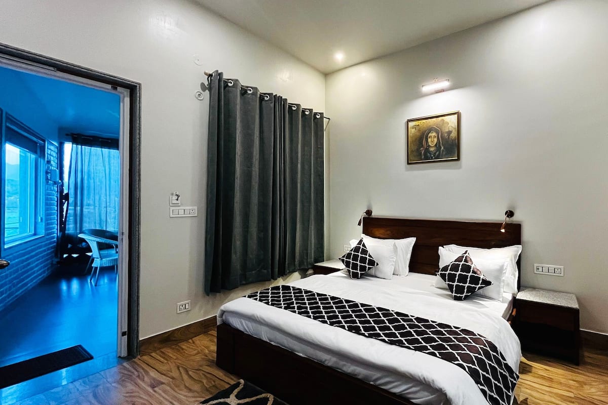 Une chambre d’hôtel avec un lit, un tableau au mur et une vue sur l’extérieur par une fenêtre.