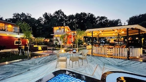 A pool area with a marble deck, outdoor seating, and a covered patio with string lights. - Vanhills : Boutique Stay in Jim Corbett (Kotabagh)