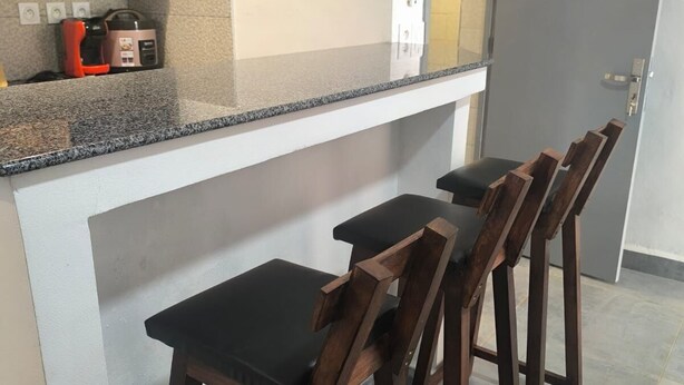 Une cuisine dotée d’un plan de travail en granit, d’un four à micro-ondes, d’une machine à café et de tabourets de bar en bois.