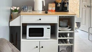Une petite cuisine équipée comprenant un four à micro-ondes, un petit réfrigérateur et une machine à café, le tout installé sur un plan de travail en bois.