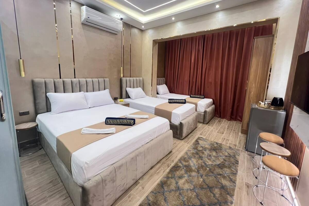 A hotel room with two beds, a desk, and a TV.