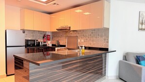 Een moderne keuken met een centraal eiland, roestvrijstalen apparatuur, een decoratieve spatwand en een grijze bank in de aangrenzende zithoek.
