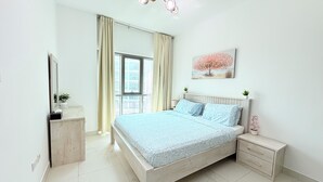Een slaapkamer met een bed, nachtkastjes, een kaptafel, een spiegel, een raam met gordijnen, een plafondlamp en een wandplant.