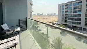Een balkon met glazen hekwerk met uitzicht op een parkeerplaats en een woestijnlandschap.