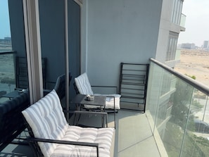 Un balcon avec un canapé, une petite table et une chaise.