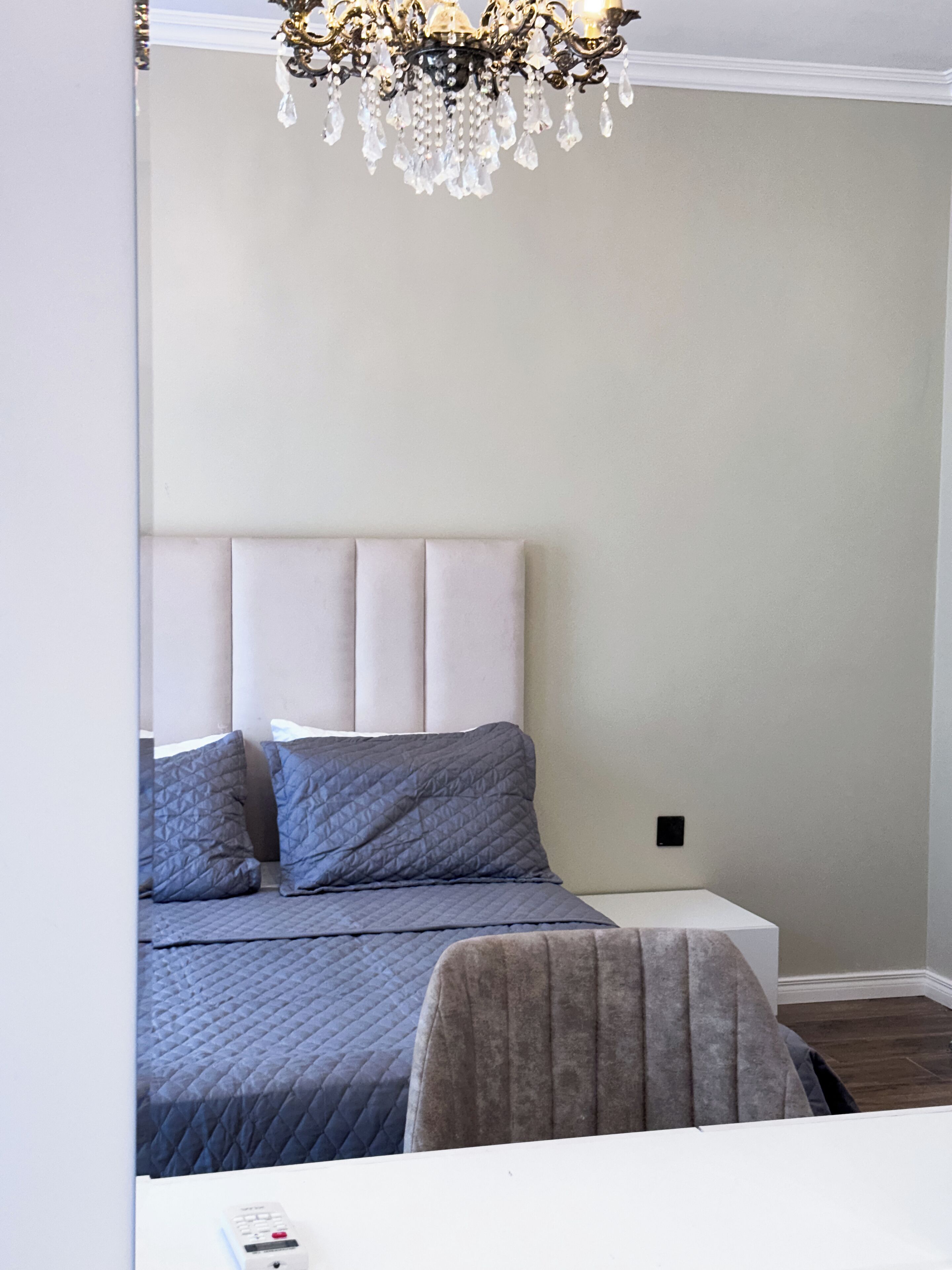 A bedroom with a bed, a chair, and a chandelier.