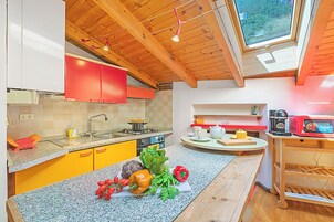 A kitchen with wooden beams, a window, and a variety of fresh produce on the counter.