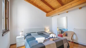 Um quarto com uma cama, mesas de cabeceira, uma cadeira, um espelho e um radiador.